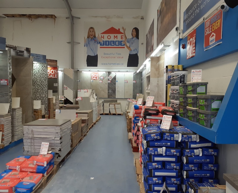 Various products such as adhesive and grout on pallets alongside rows of tiles