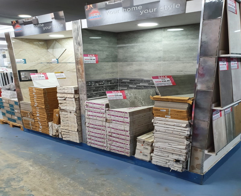 Tile displays that are fixed to the wall with stock piled in front of them