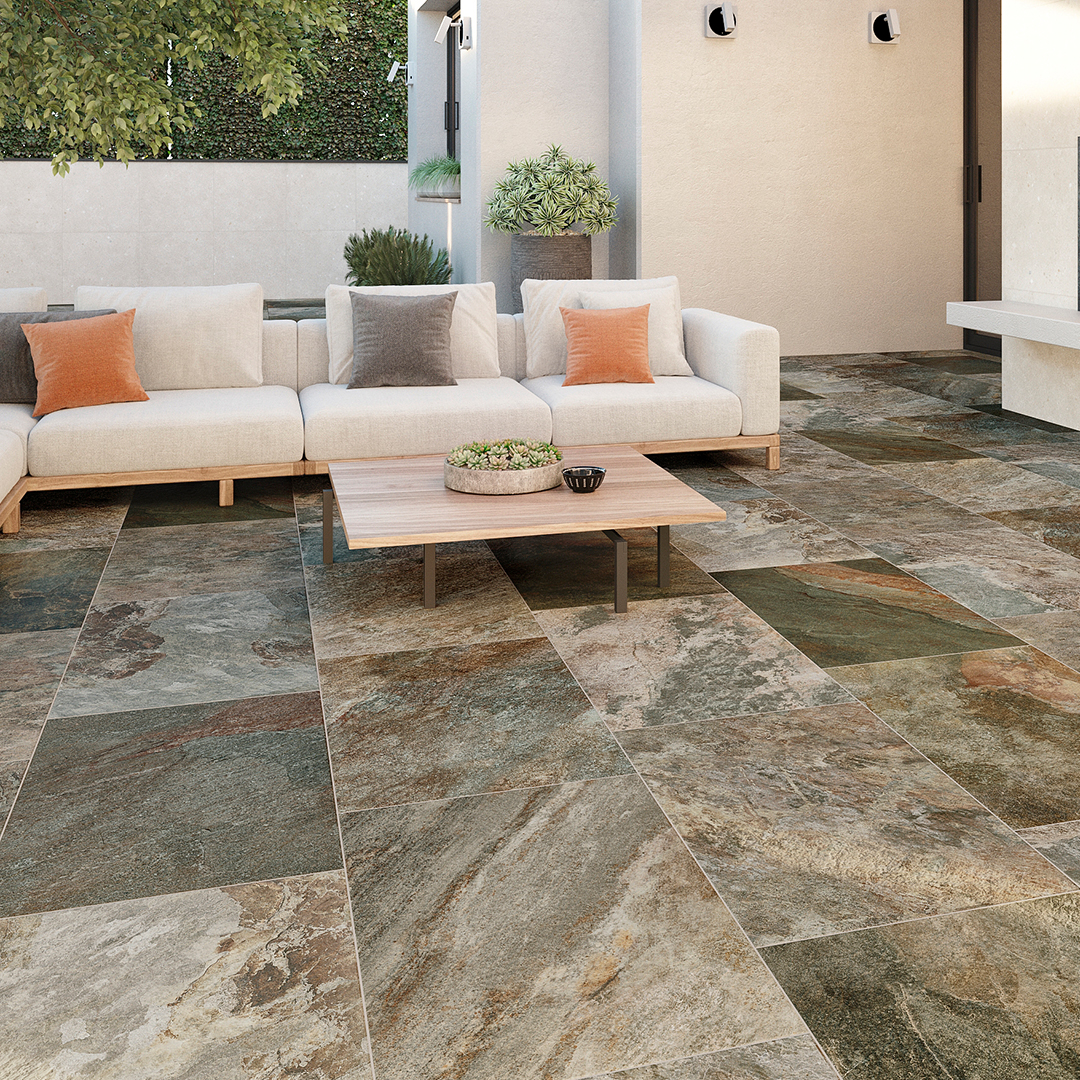 Outdoor patio with a dark, flagstone looking tile and a lounge set and table.